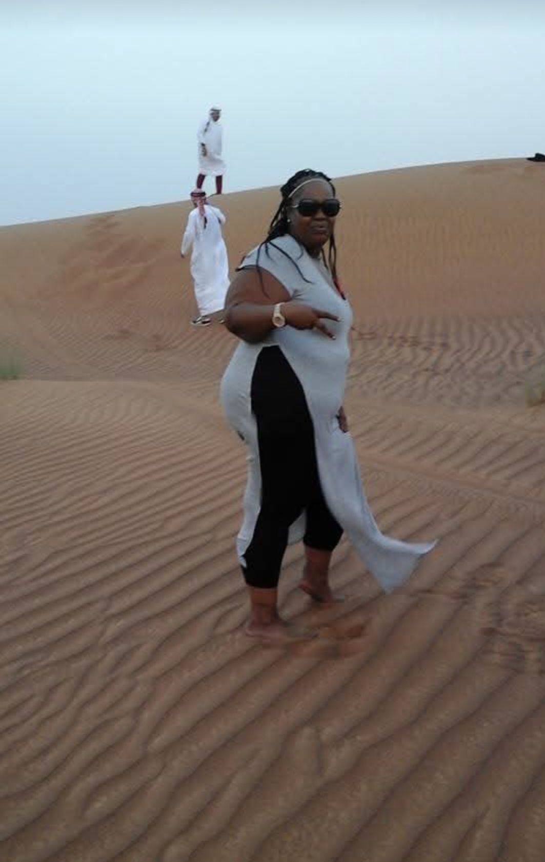 A woman is standing on top of a sand dune.