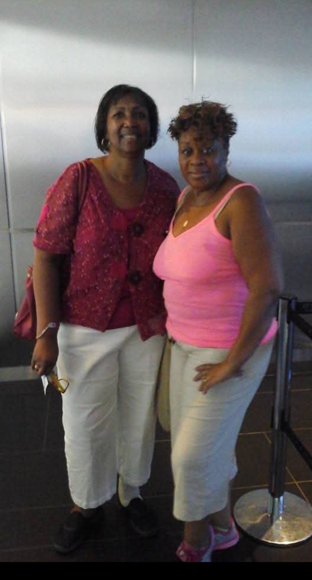 Two women are posing for a picture and one is wearing a pink tank top