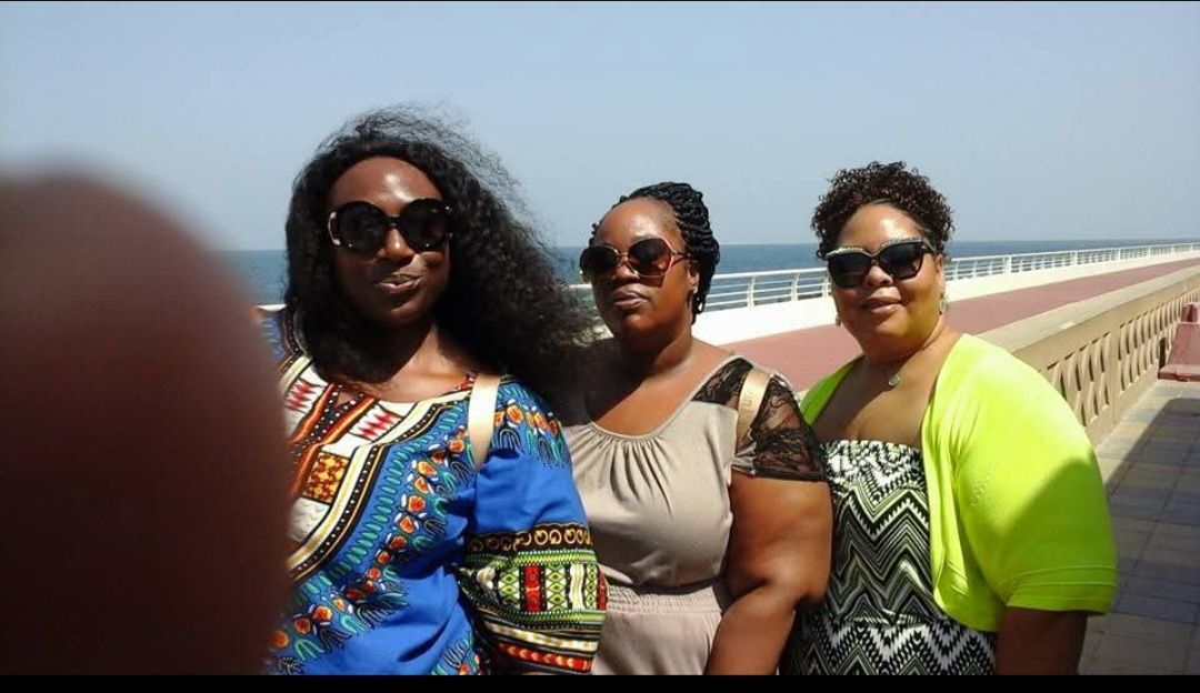 Three women wearing sunglasses are standing next to each other on a sidewalk.