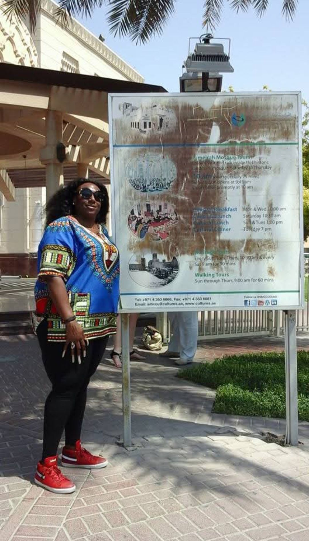 A woman is standing in front of a large sign.