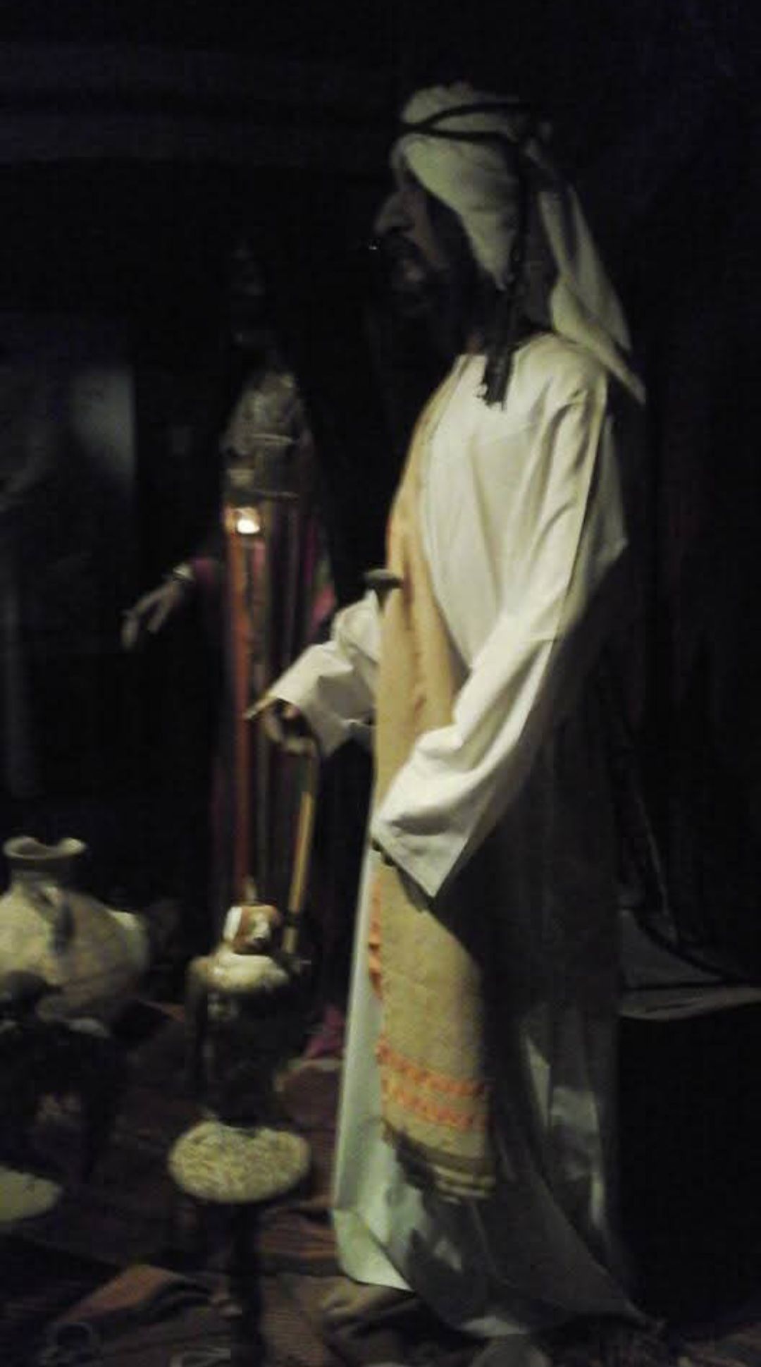 A man in a white robe is standing in a dark room