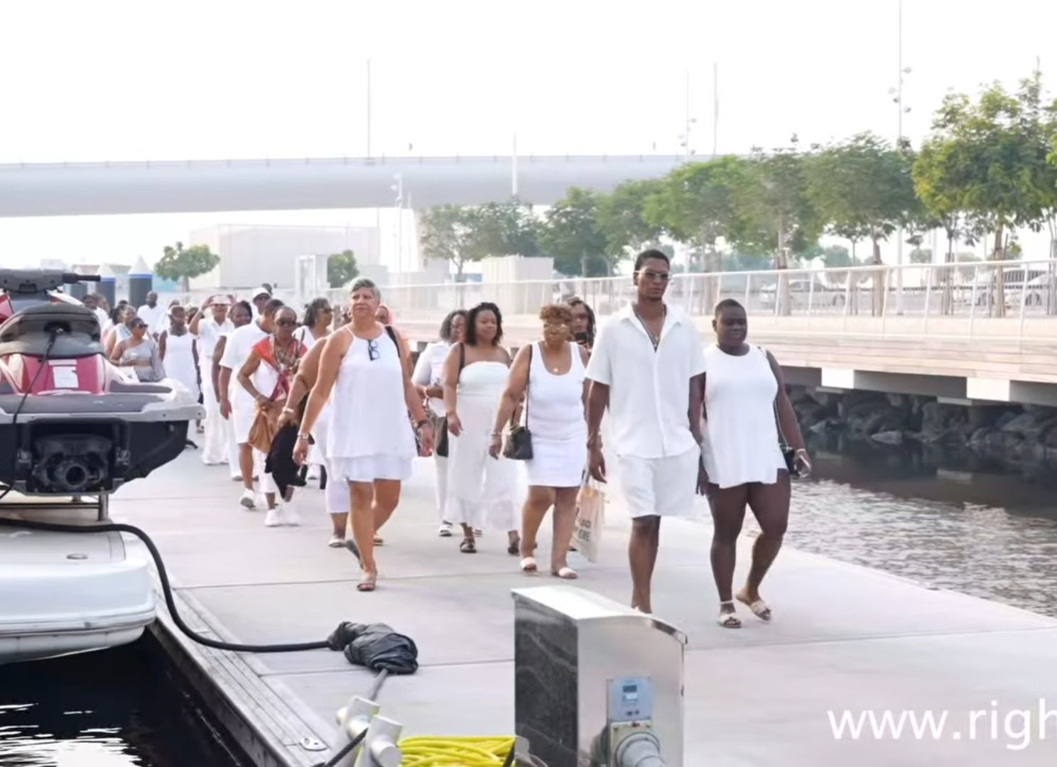 A group of people wearing white walking on a dock