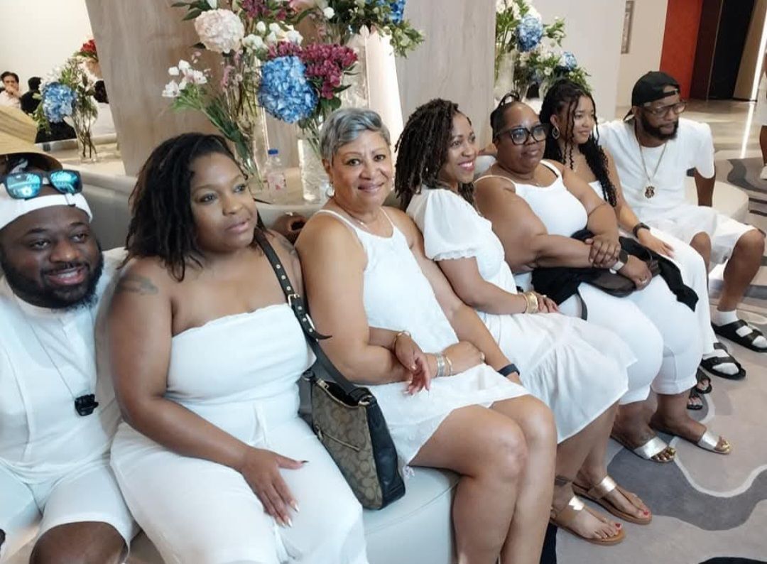 A group of people in white dresses are sitting on a couch.