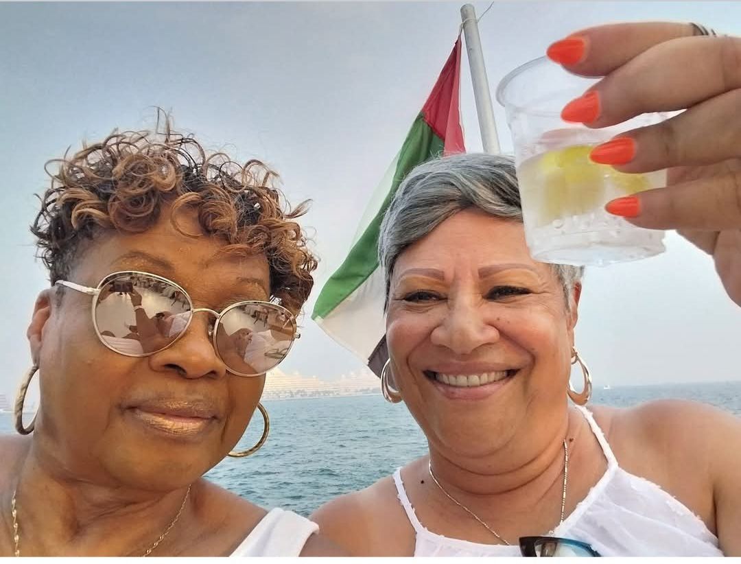 Two women are posing for a picture and one is holding a shot glass