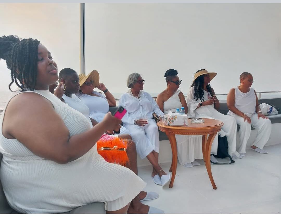 A group of women in white dresses are sitting around a table.