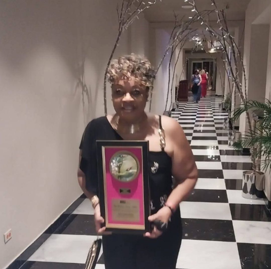 A woman is holding a plaque in a hallway