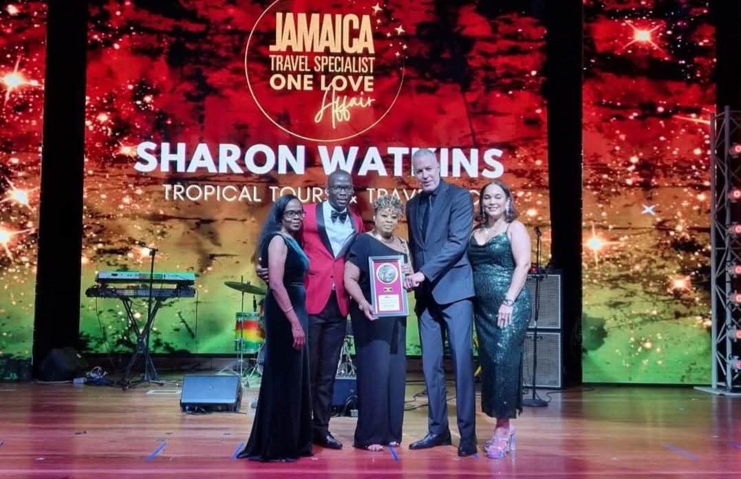 A group of people are standing on a stage in front of a large screen.