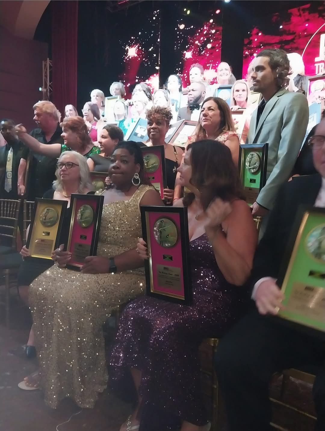 A group of people are sitting in chairs holding plaques