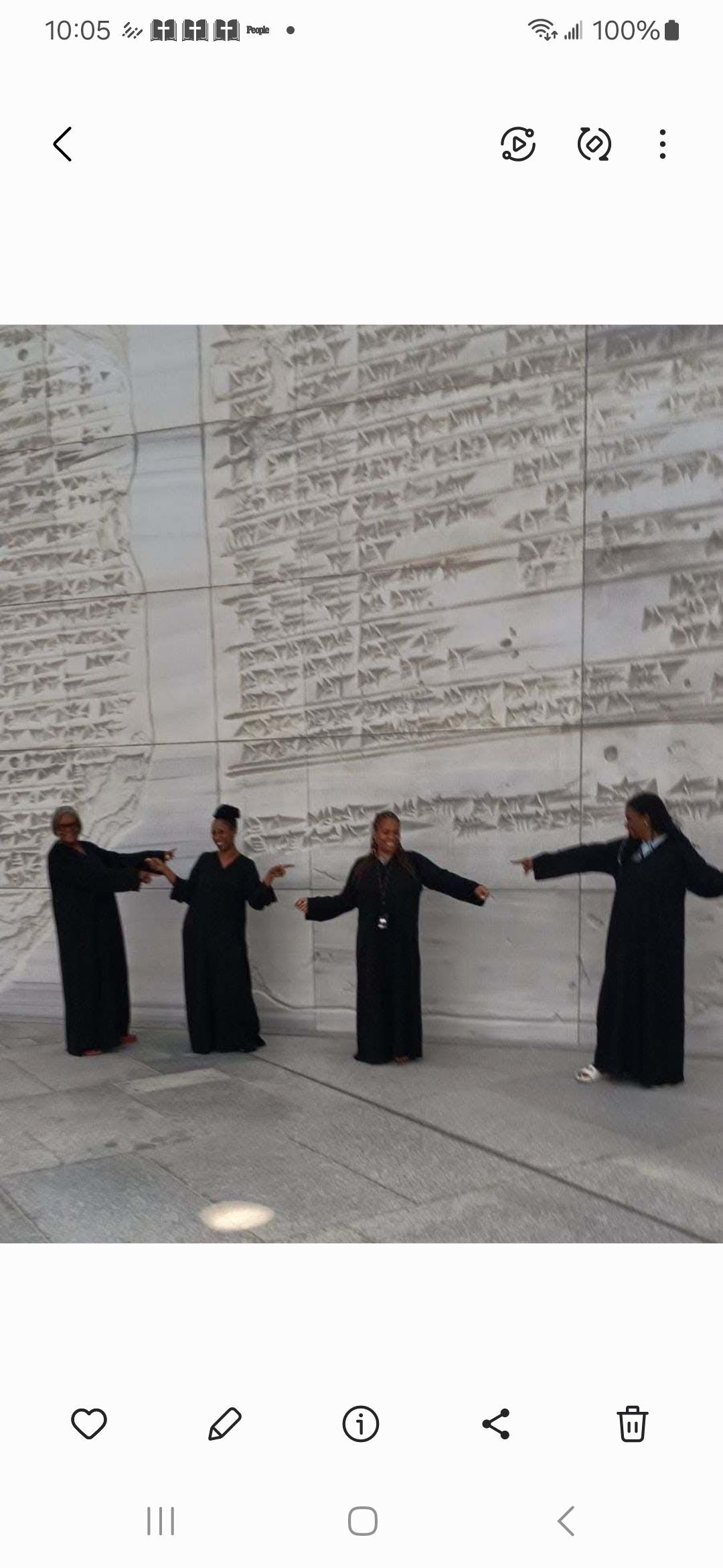 A group of people are standing in front of a wall.