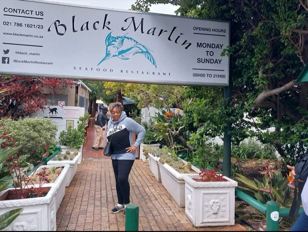 A woman stands in front of a sign that says black marlin