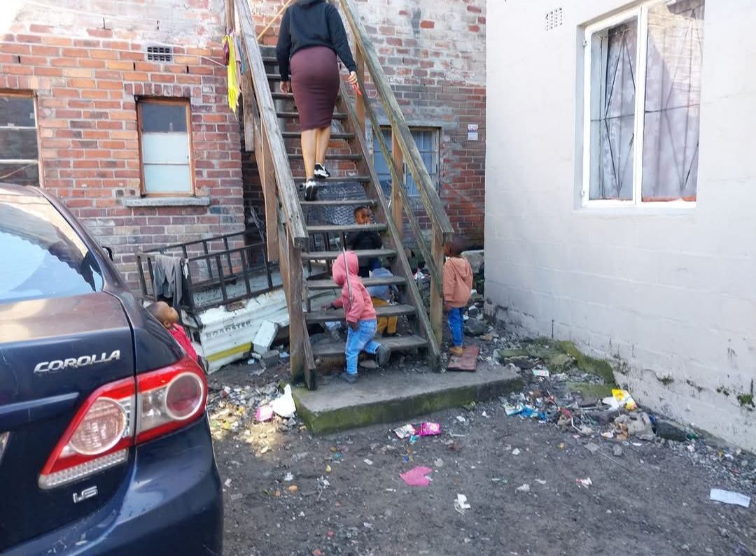 A woman is walking up a set of stairs next to a car.