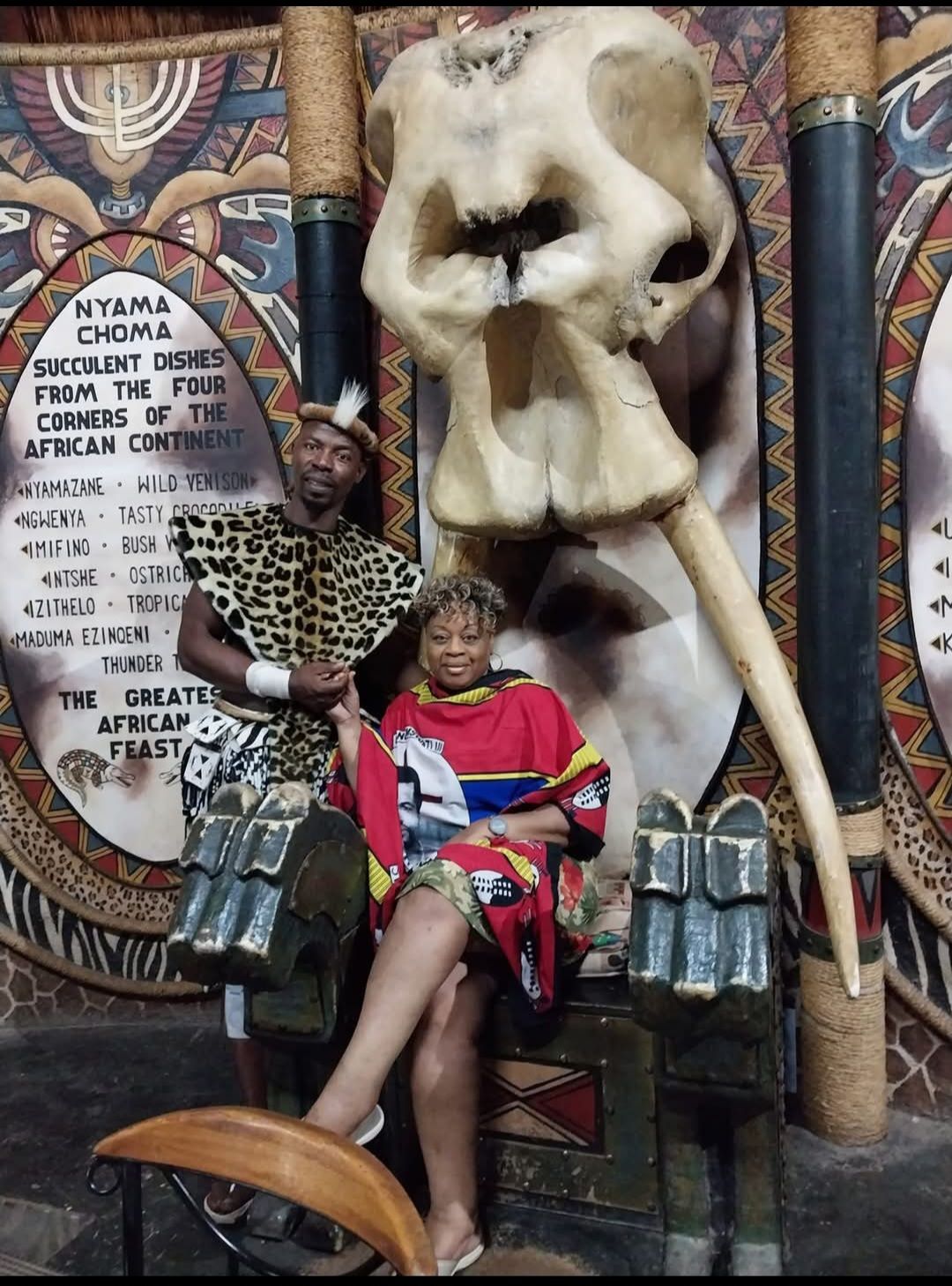 A woman sits in front of a large elephant skull