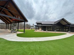 Courtyard with green turf patches between concrete walkways, white benches, and building in the background.
