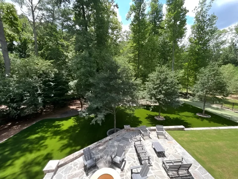 Patio with stone pavers, fire pit, and seating overlooking a green lawn and trees.