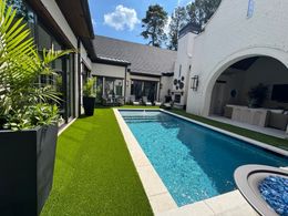 Backyard of a house with a lush green lawn, brick chimney, and clear blue sky.