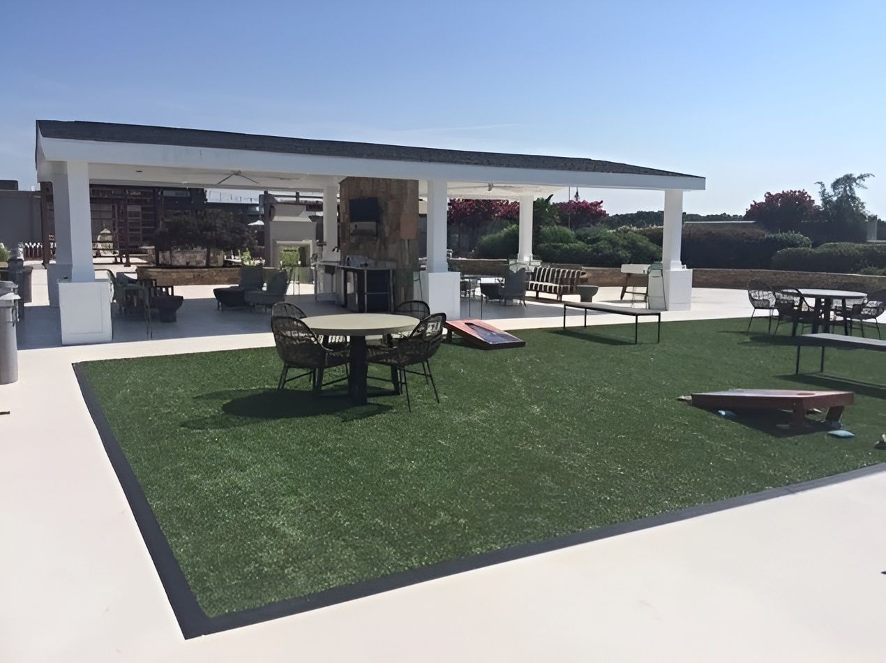 Outdoor recreational area with artificial turf, seating, and a pergola.