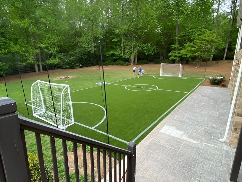 Soccer field in a backyard with two goals. Children play soccer on green turf.