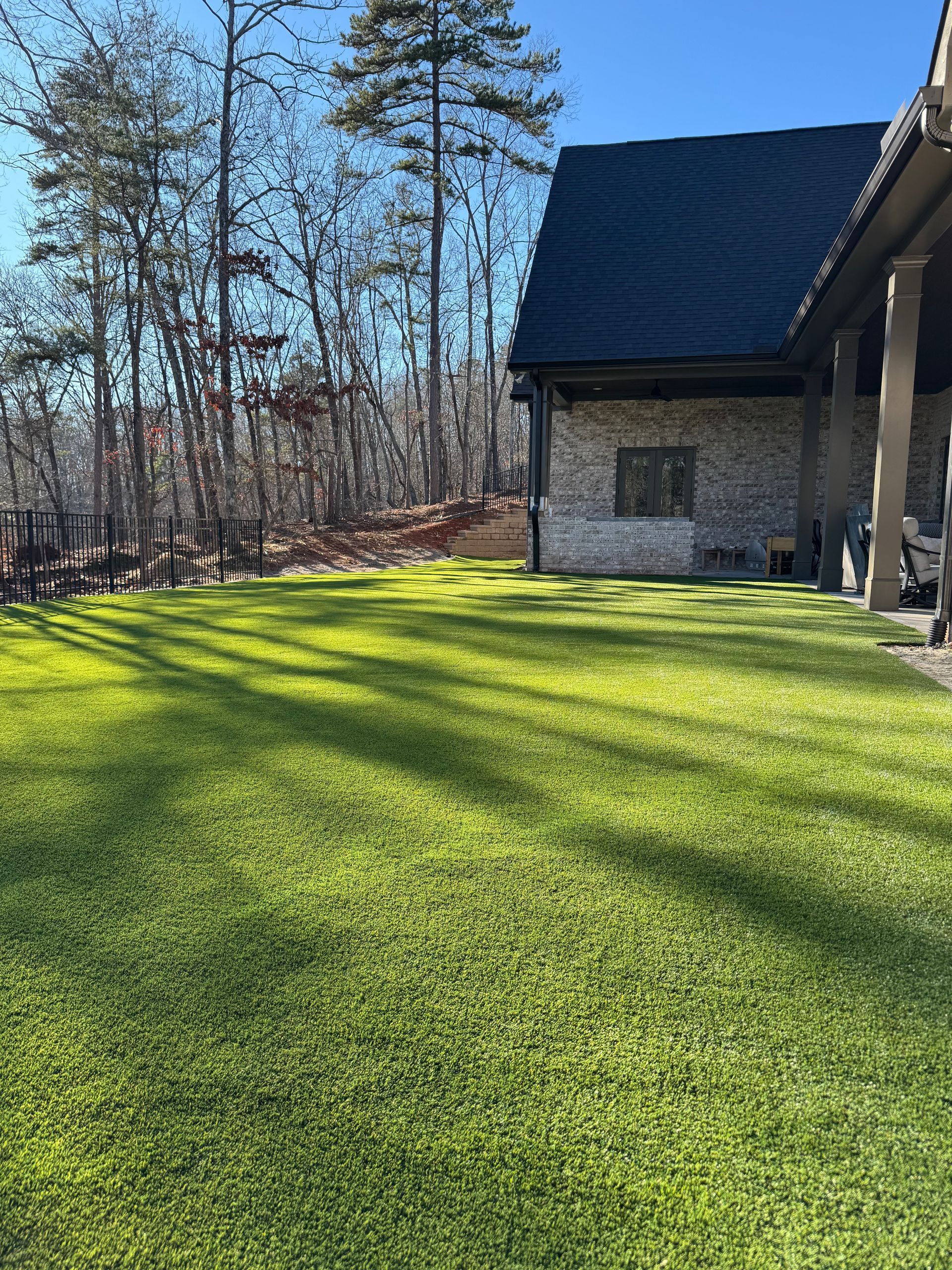 Bright green lawn next to a brick building under a sunny sky.