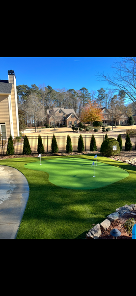 Patio with stone pavers, fire pit, and seating overlooking a green lawn and trees.