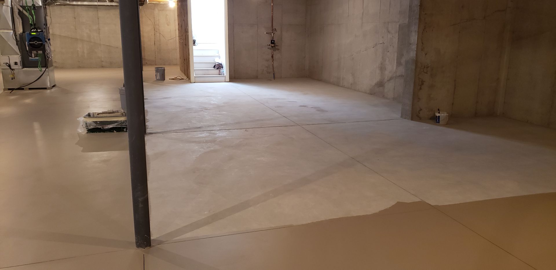 A basement with a concrete floor and a metal pole.