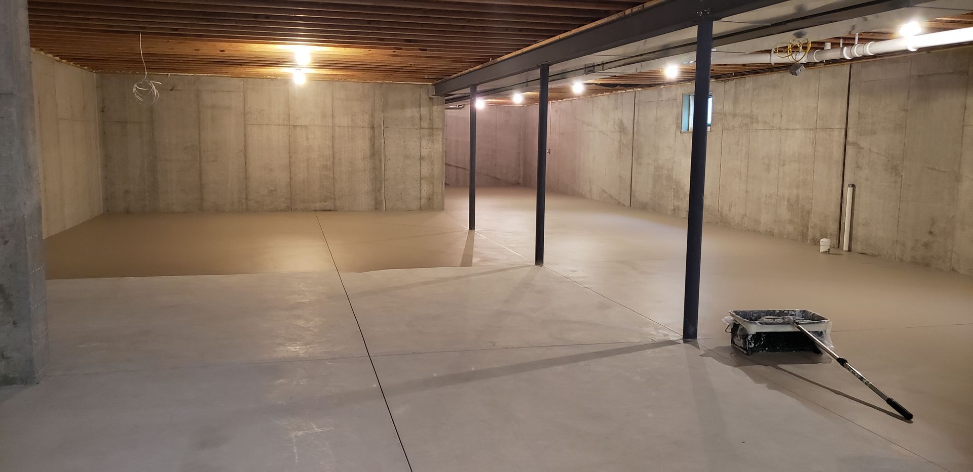 An empty basement with a vacuum cleaner sitting on the floor.