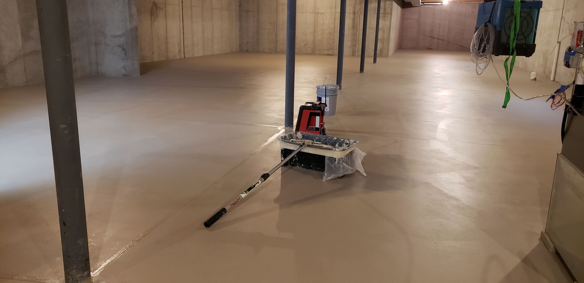 A person is cleaning a basement floor with a mop.