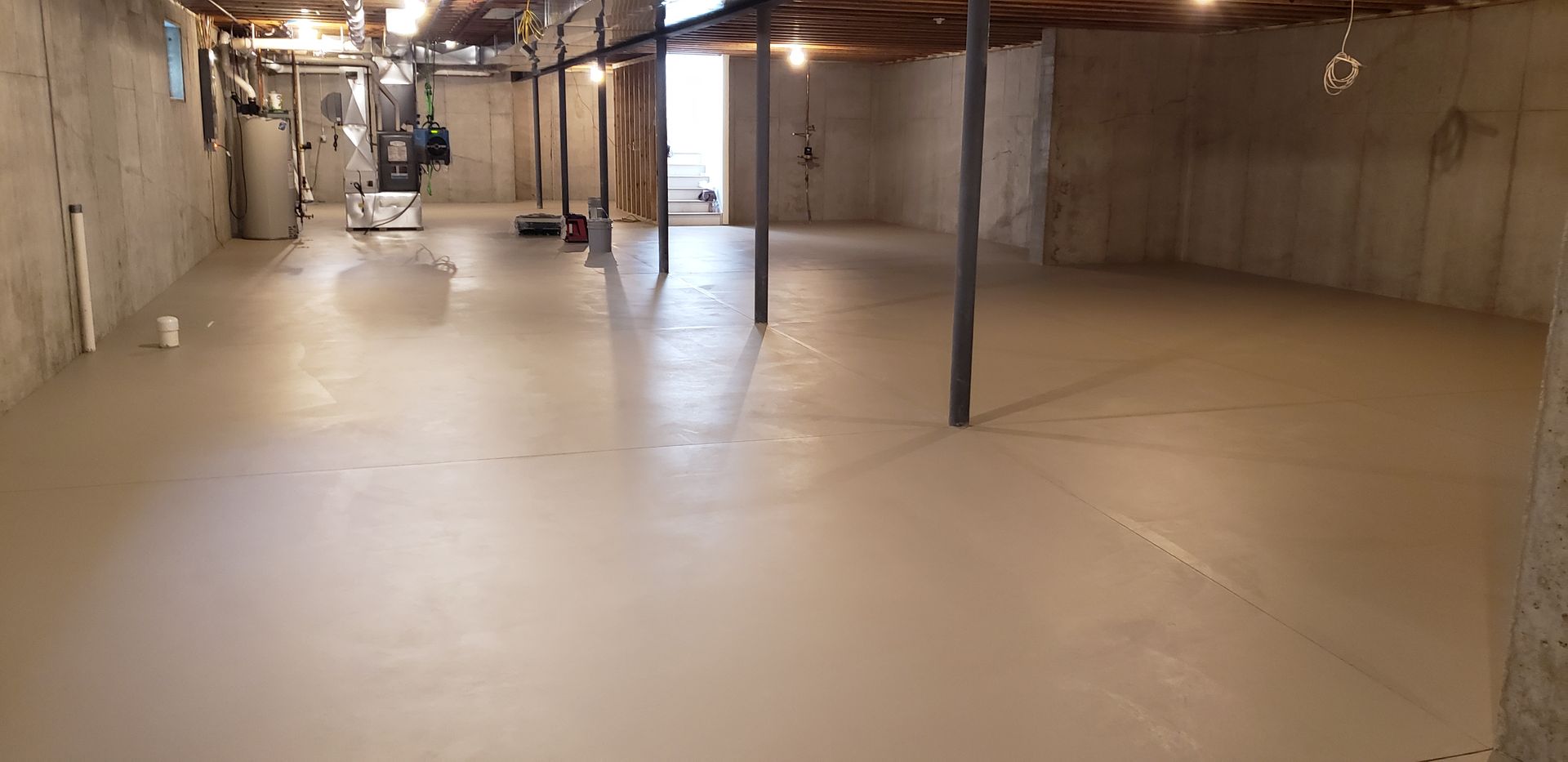 A large empty basement with a concrete floor and ceiling.