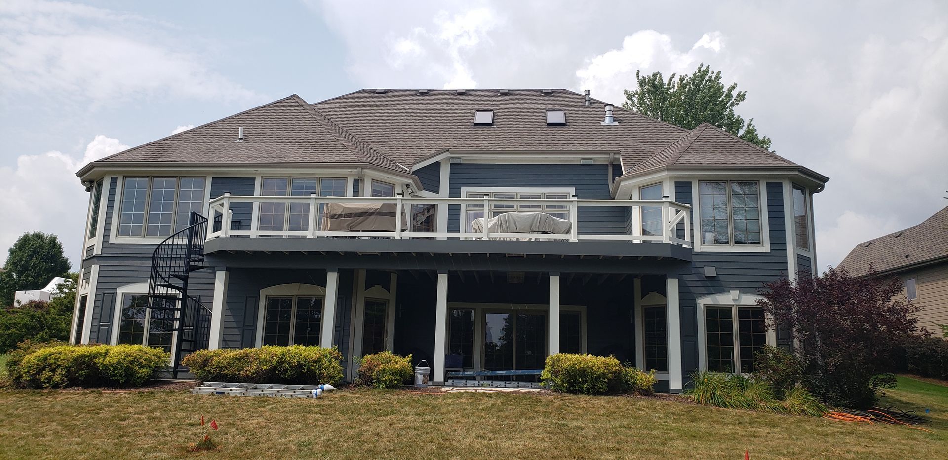 The back of a large house with a large deck and stairs.