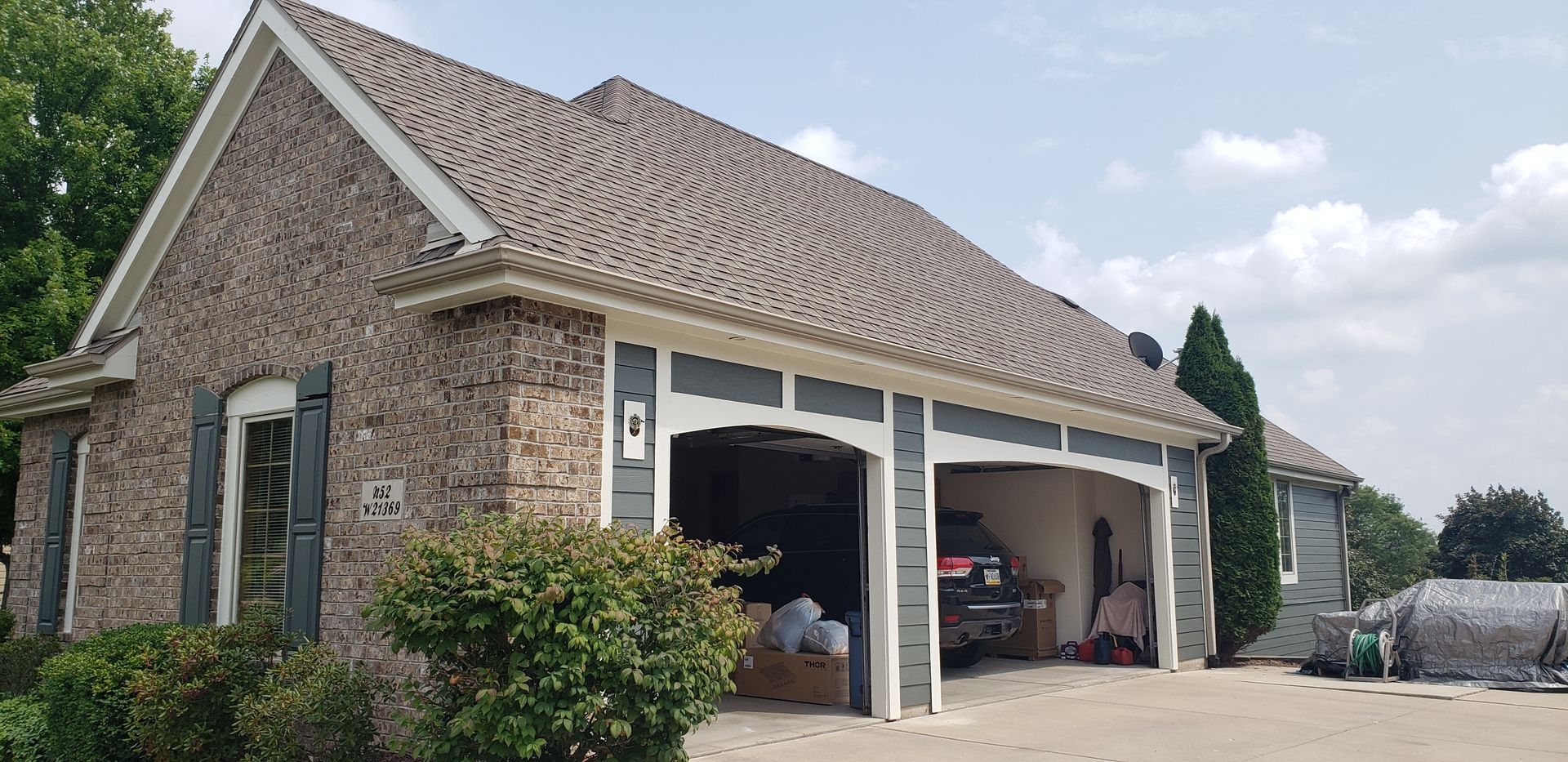 A large brick house with a garage and a car parked in it.