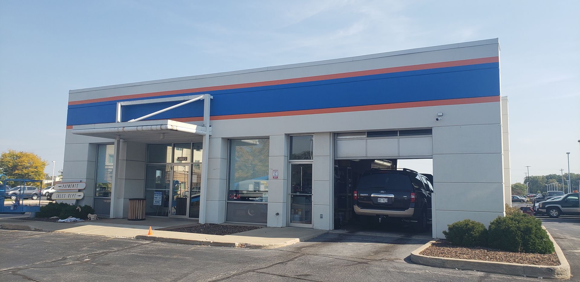 A white and blue building with a car parked in front of it.