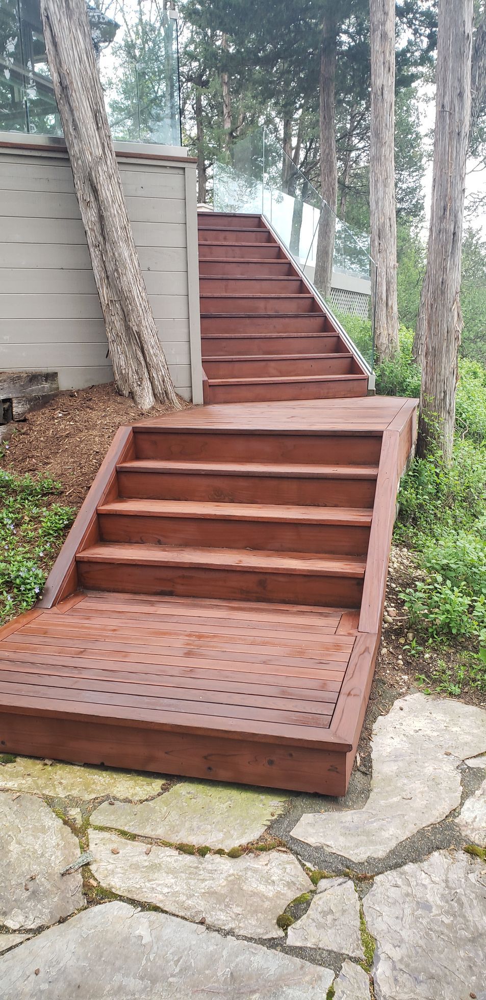 A wooden deck with stairs leading up to it surrounded by trees.