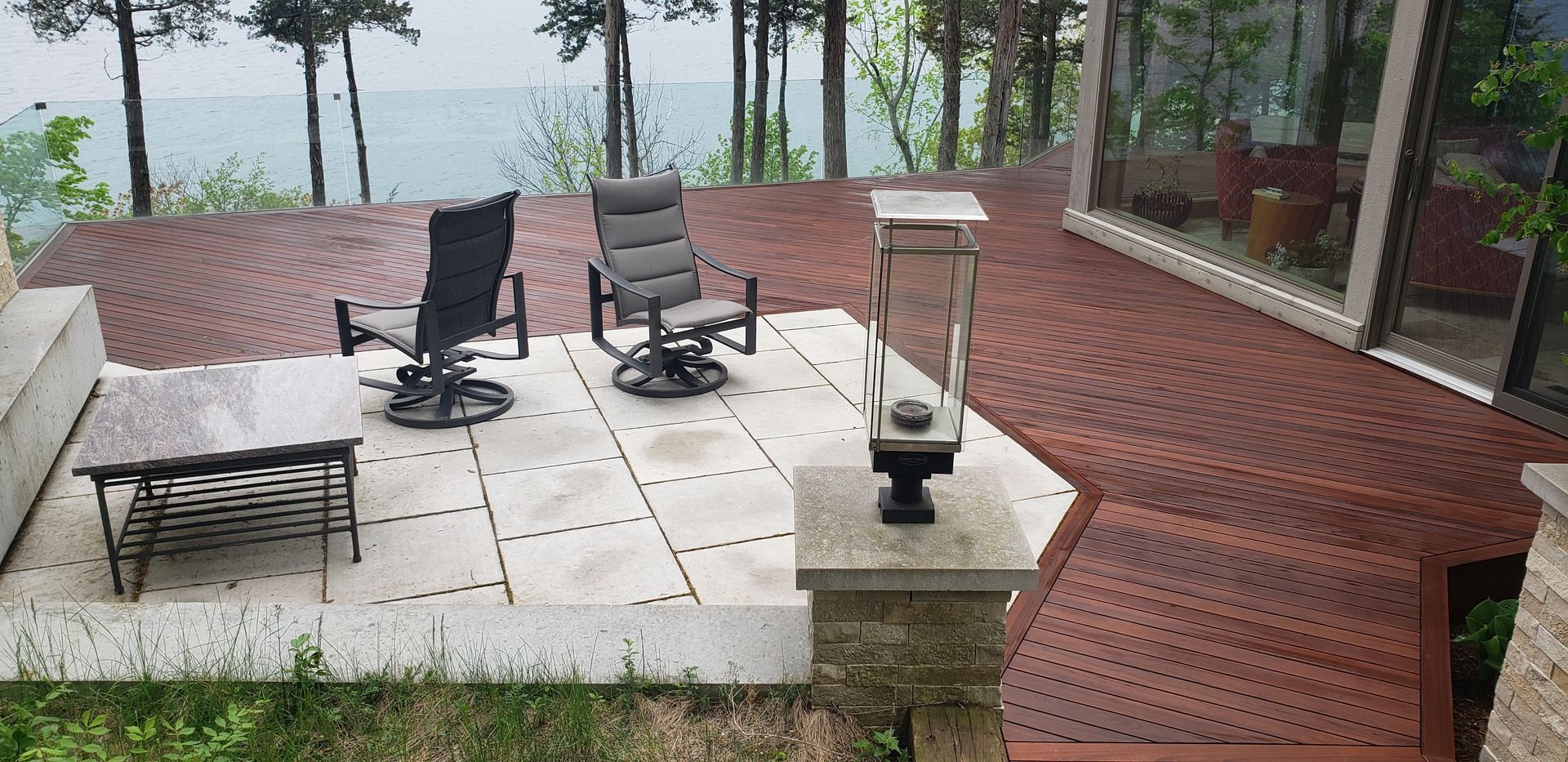 A patio with chairs and a table overlooking a lake.