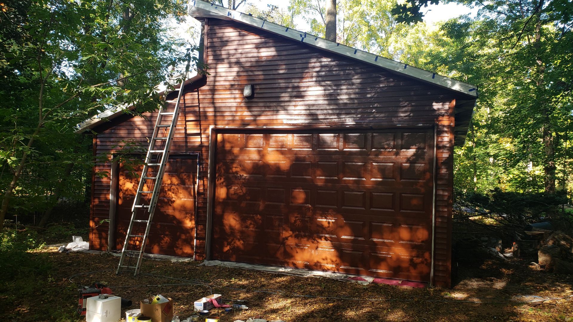 A garage is being painted with a ladder.