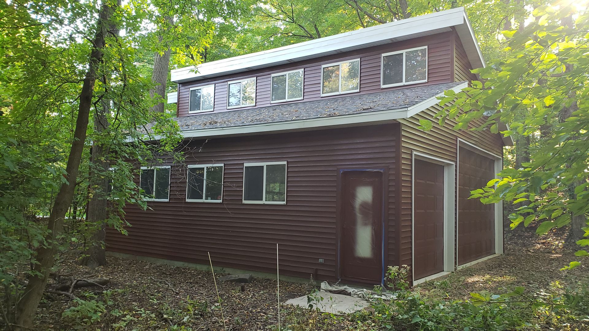 A small house in the middle of a forest surrounded by trees.
