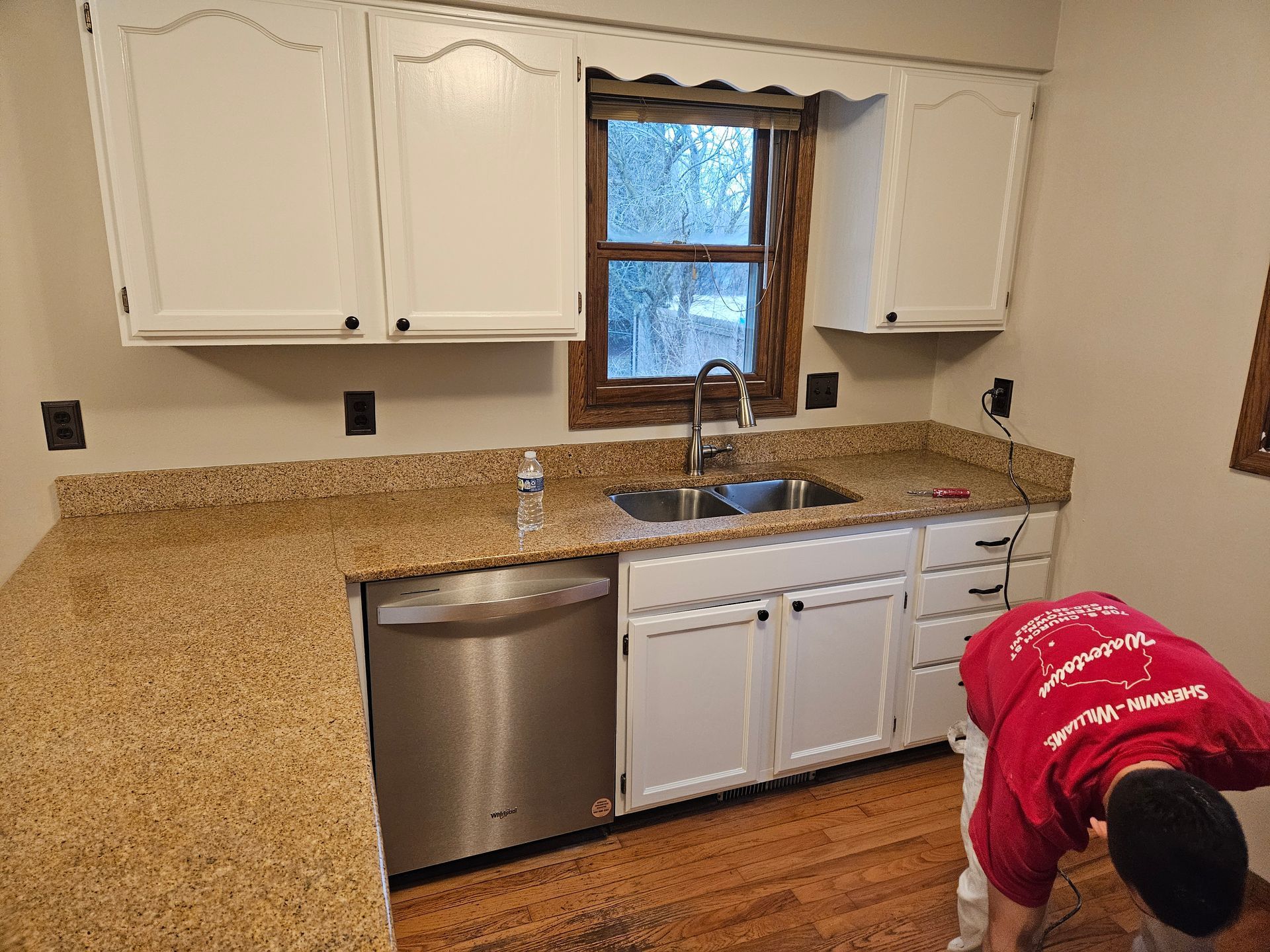 A man in a red shirt is working in a kitchen.