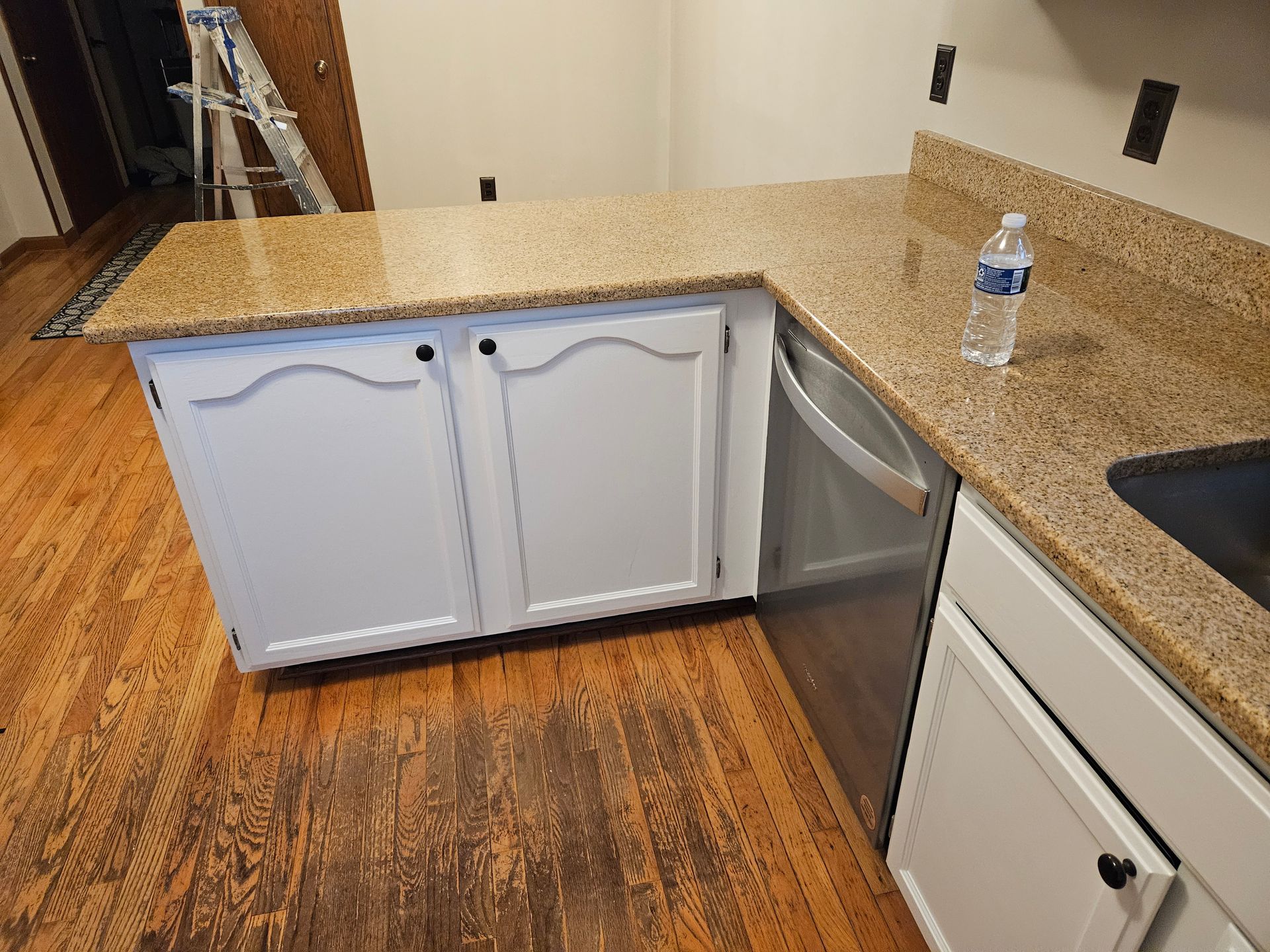 There is a bottle of water on the counter in the kitchen.