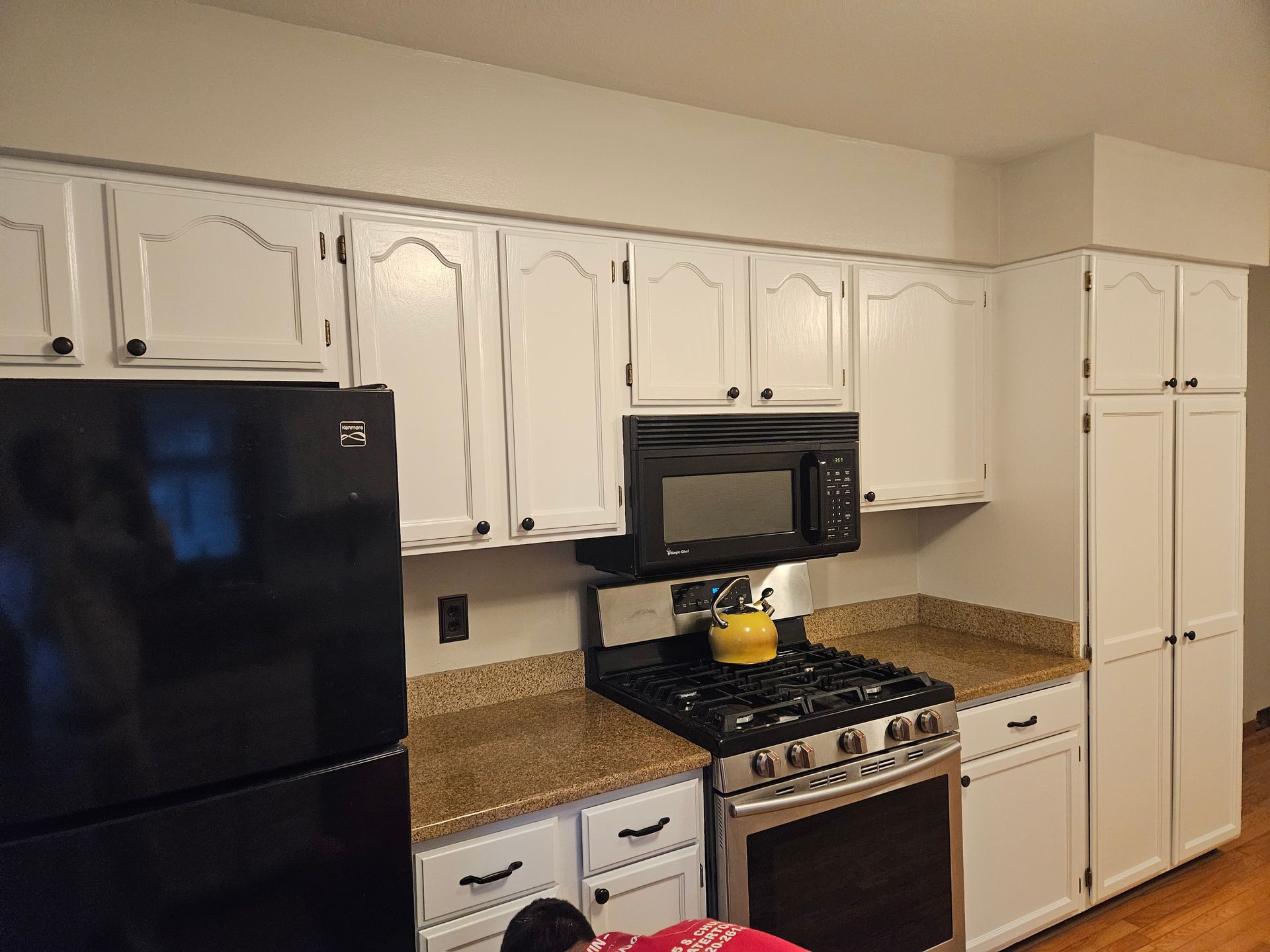 A kitchen with white cabinets and a black refrigerator