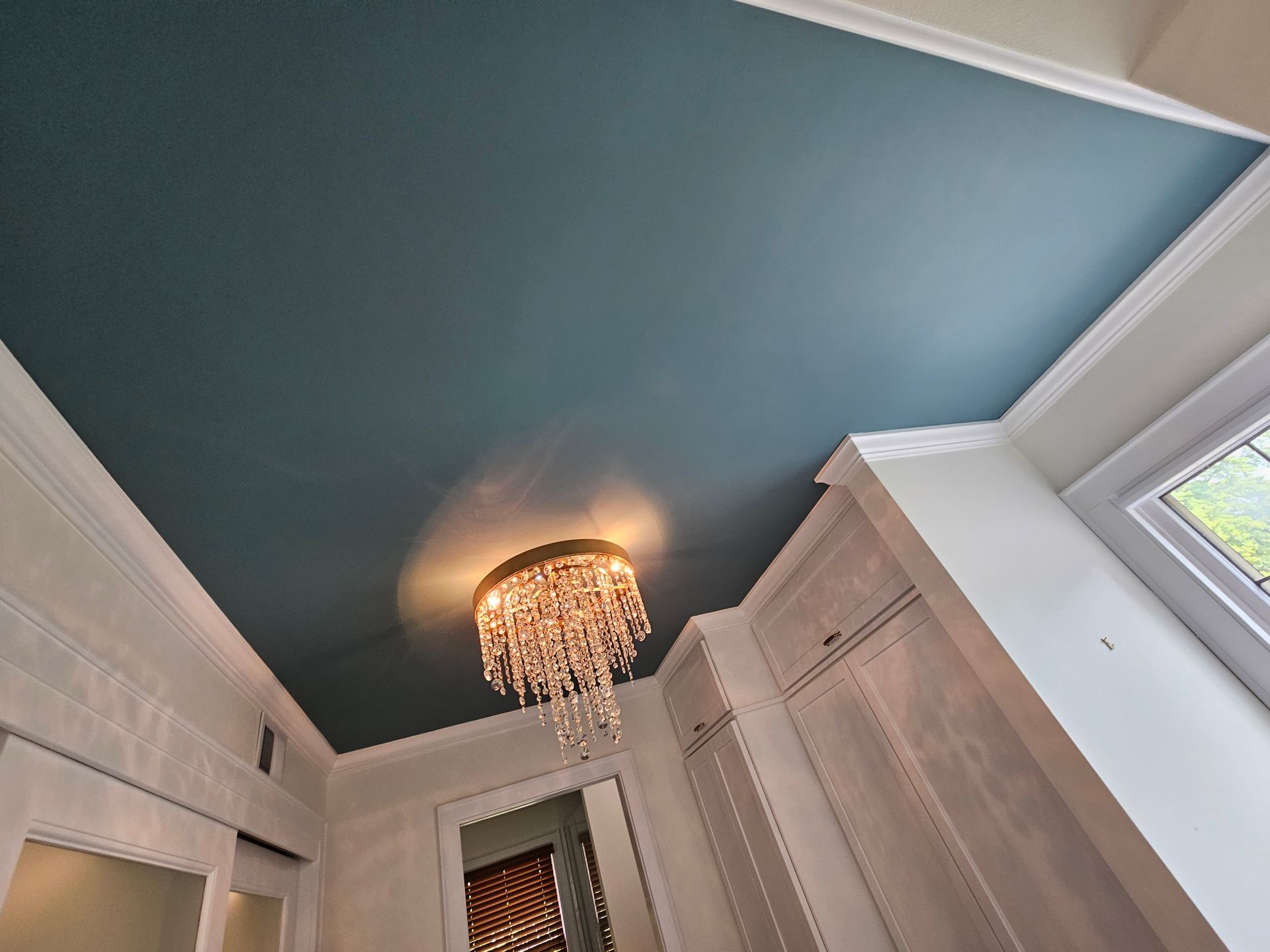 A blue ceiling with a chandelier hanging from it