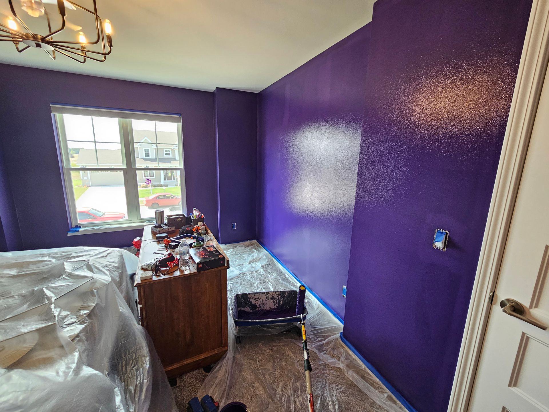 A bedroom with purple walls is being painted.