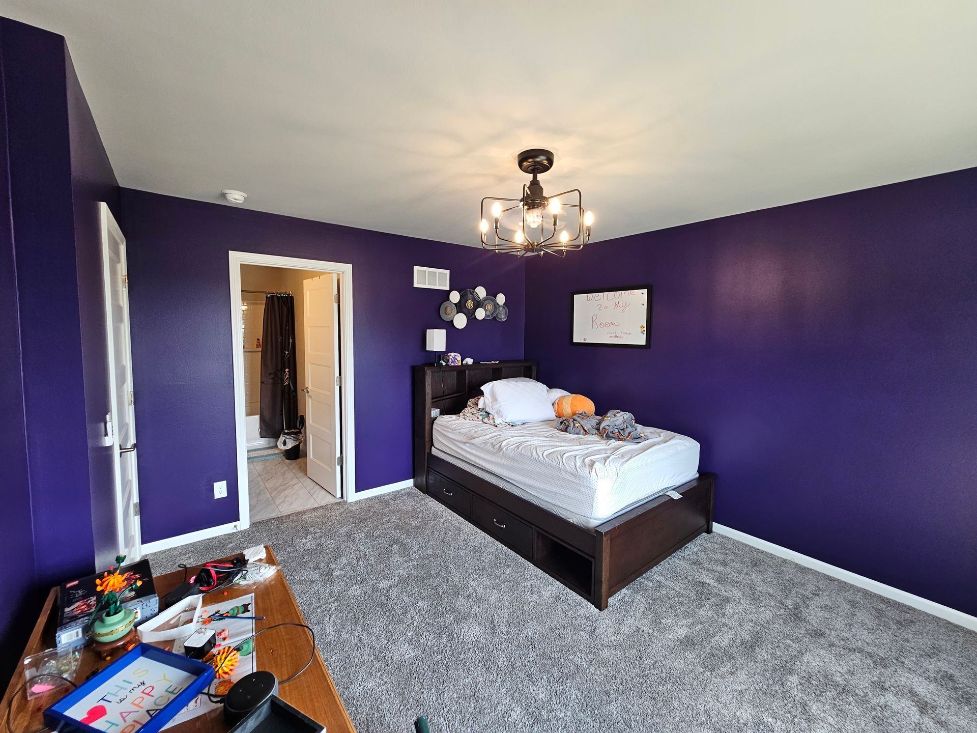 A bedroom with purple walls and a bed.