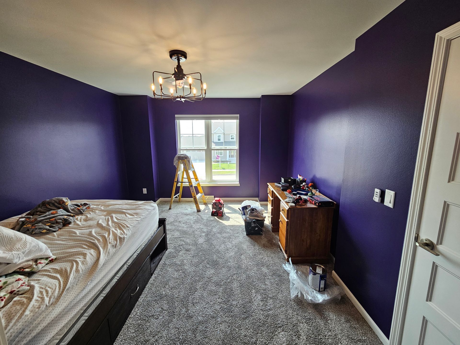 A bedroom with purple walls and a bed.
