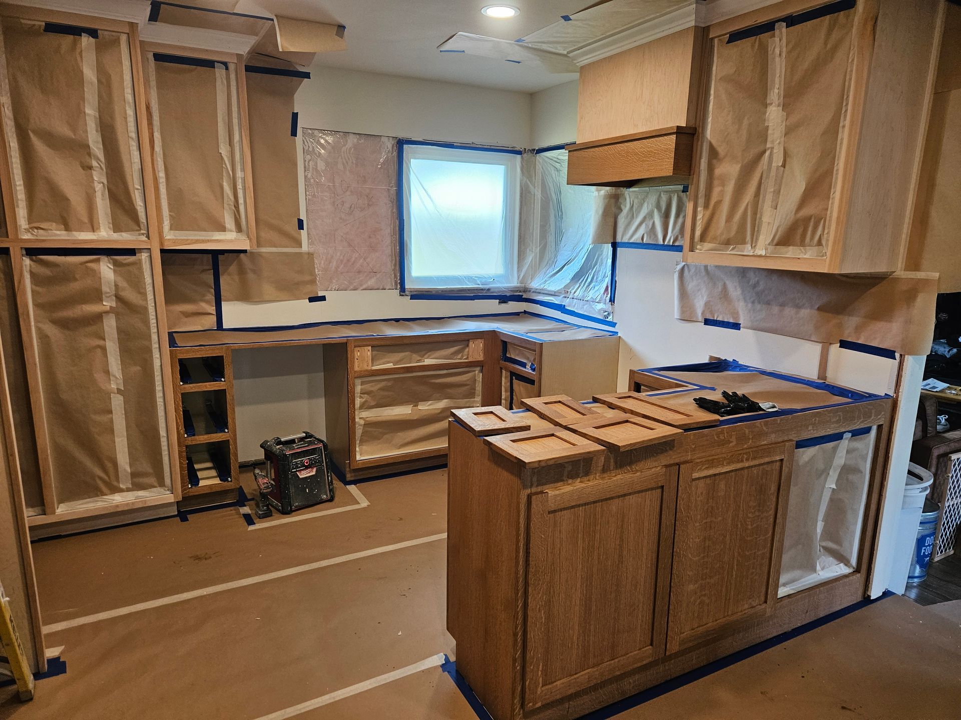 A kitchen under construction with wooden cabinets and a window.