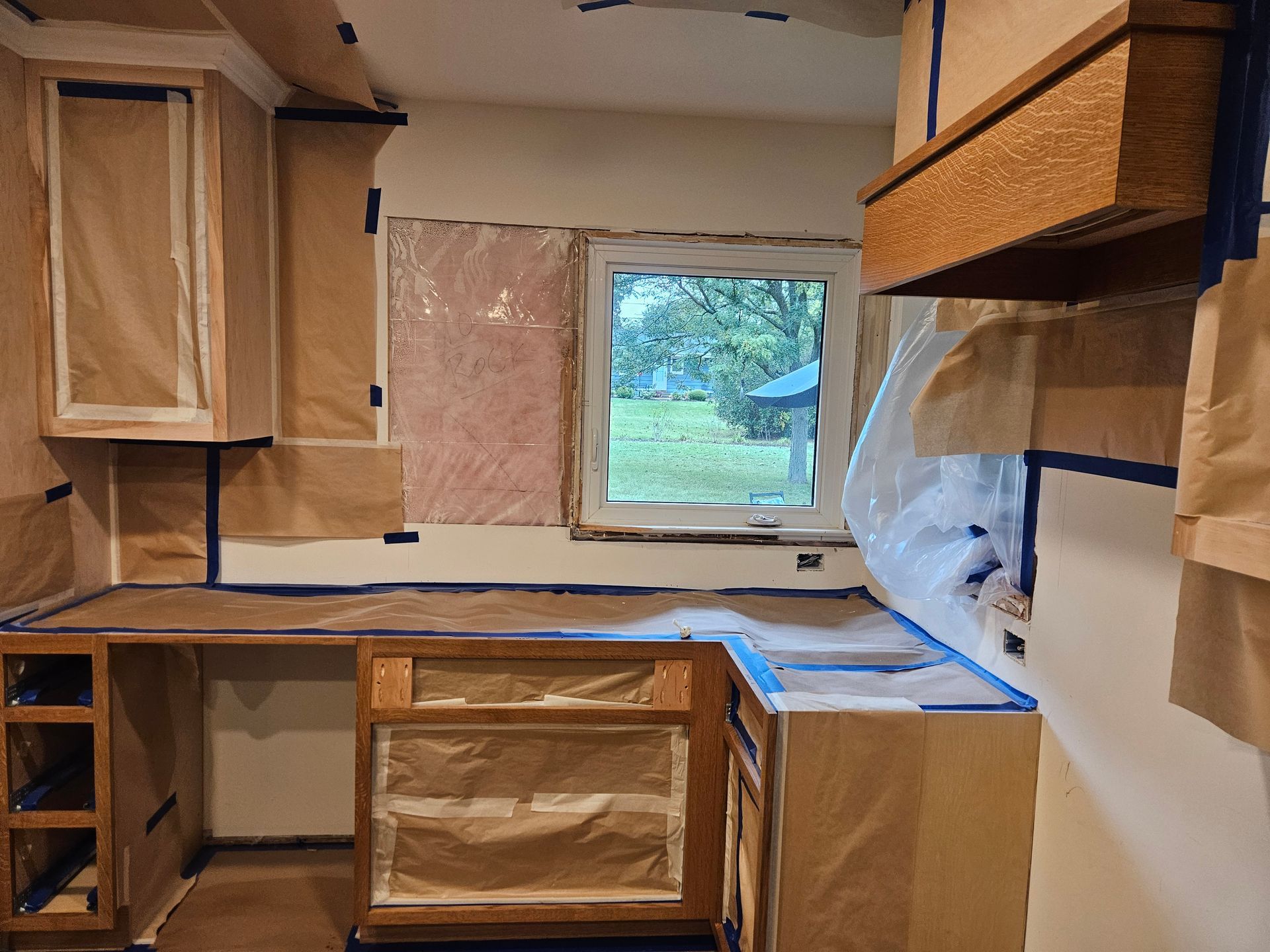 A kitchen is being remodeled with wooden cabinets and a window.
