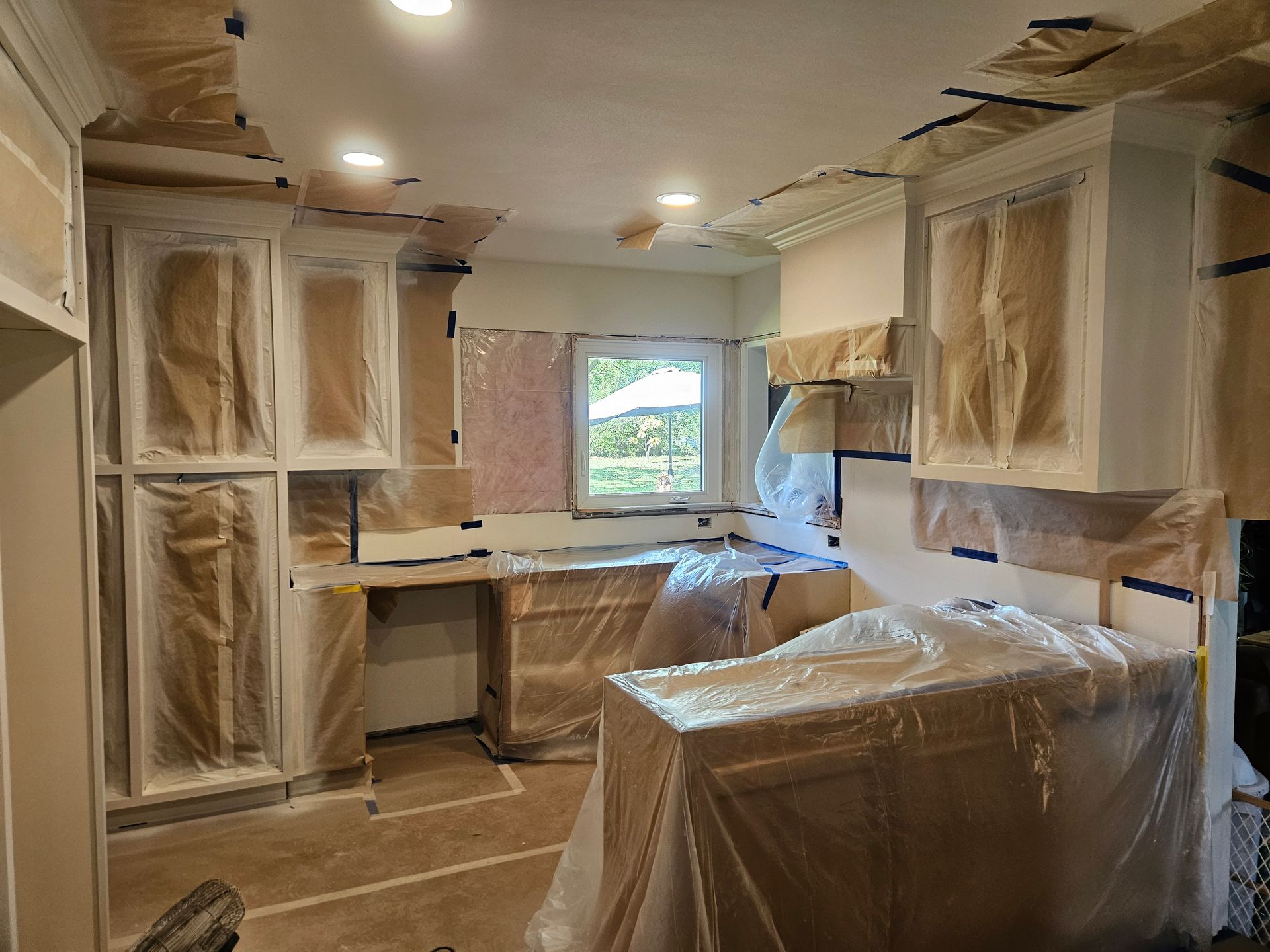 A kitchen is being painted and covered in plastic.
