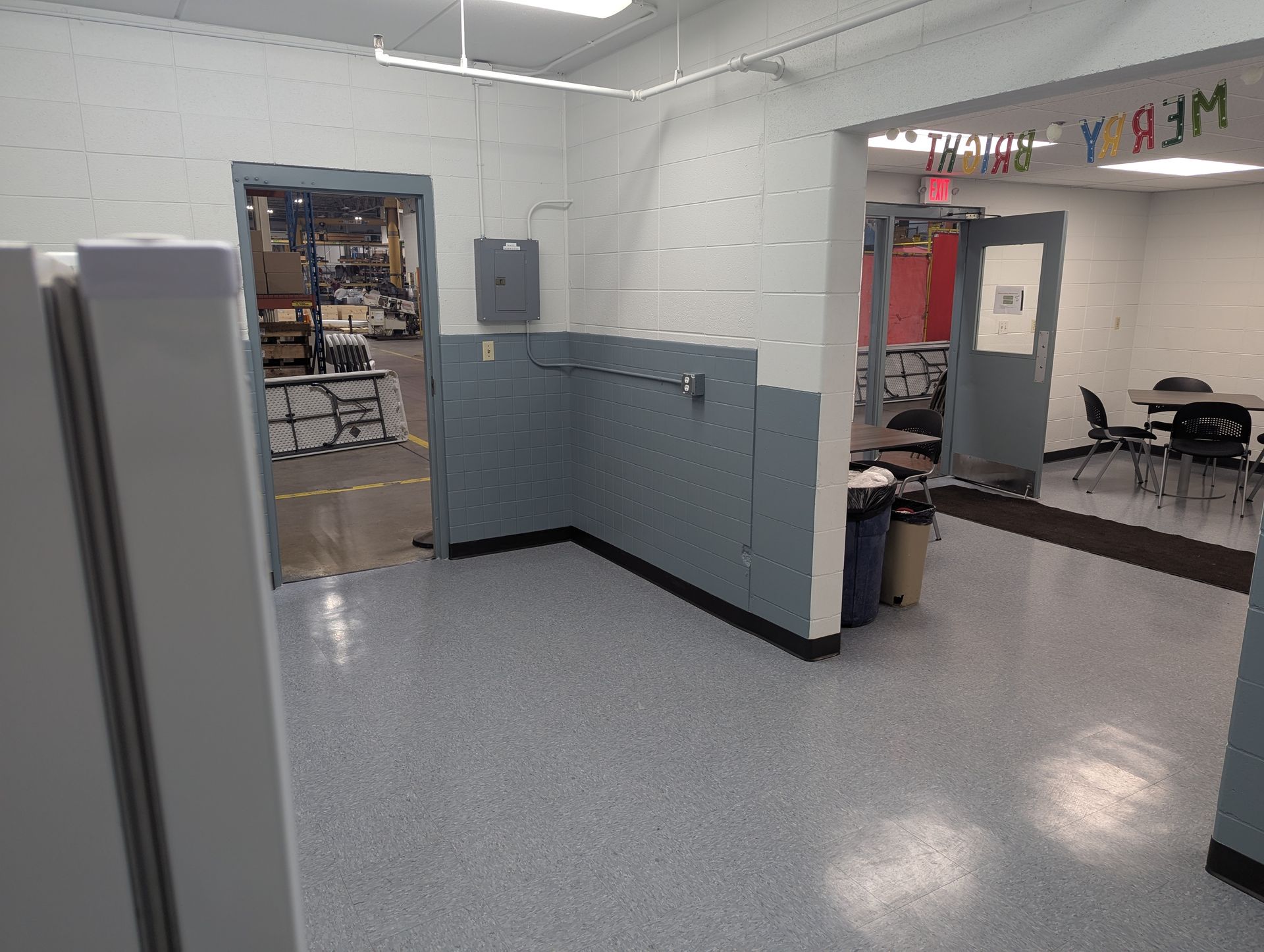 A room with an open doorway, grey walls, a coat rack, and an open doorway to another room.