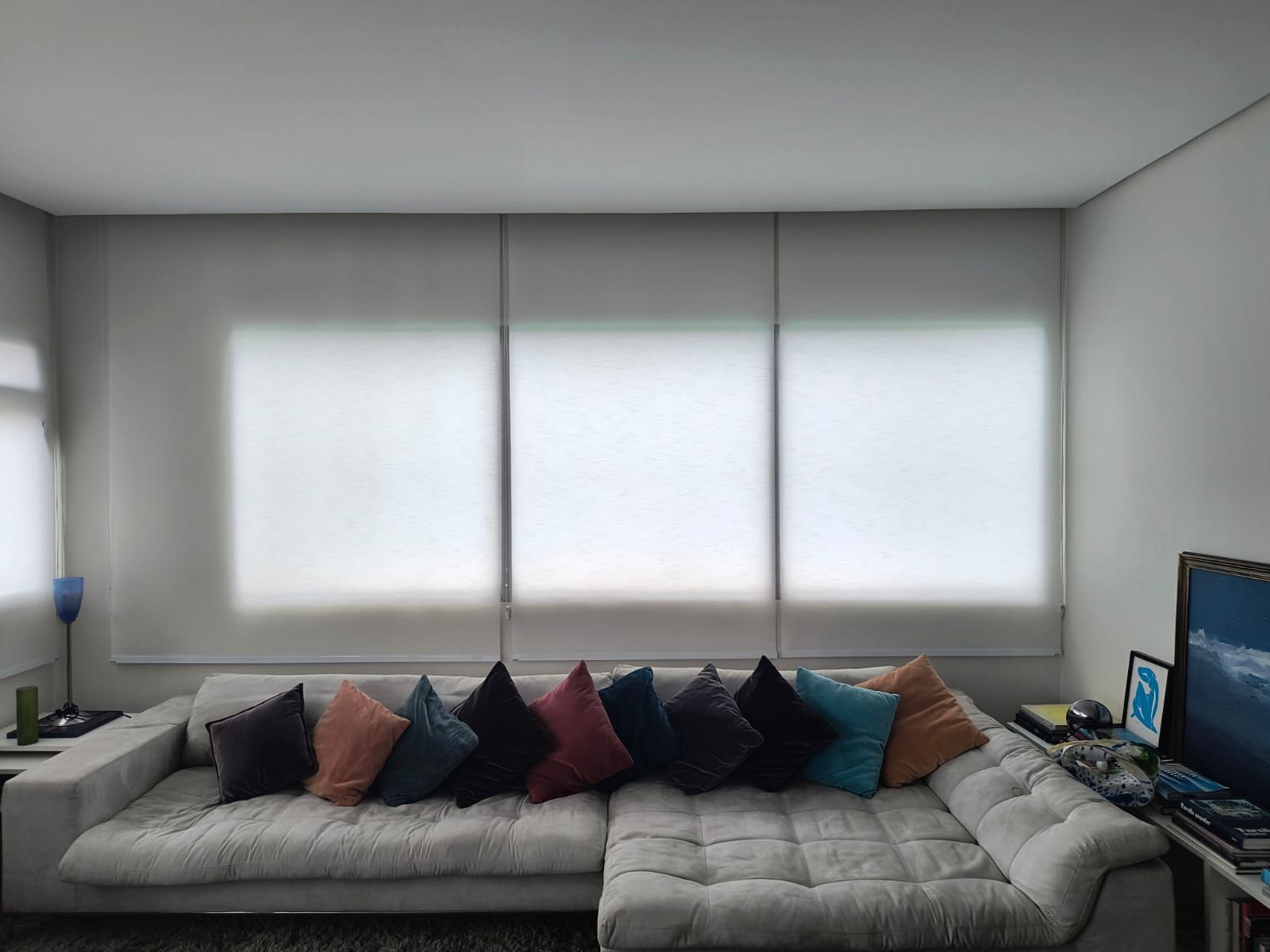 Um quarto com cama, mesa de cabeceira, abajur e persiana.