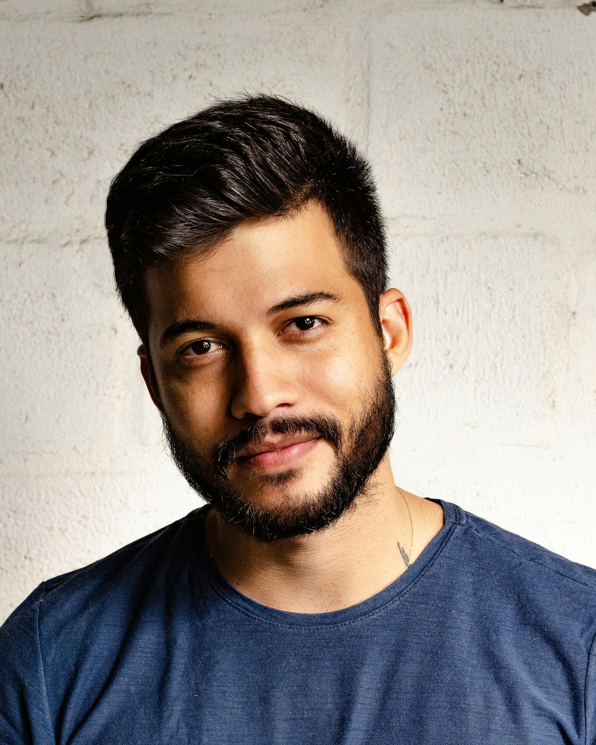 Um homem com barba está vestindo uma camisa azul e olhando para a câmera.