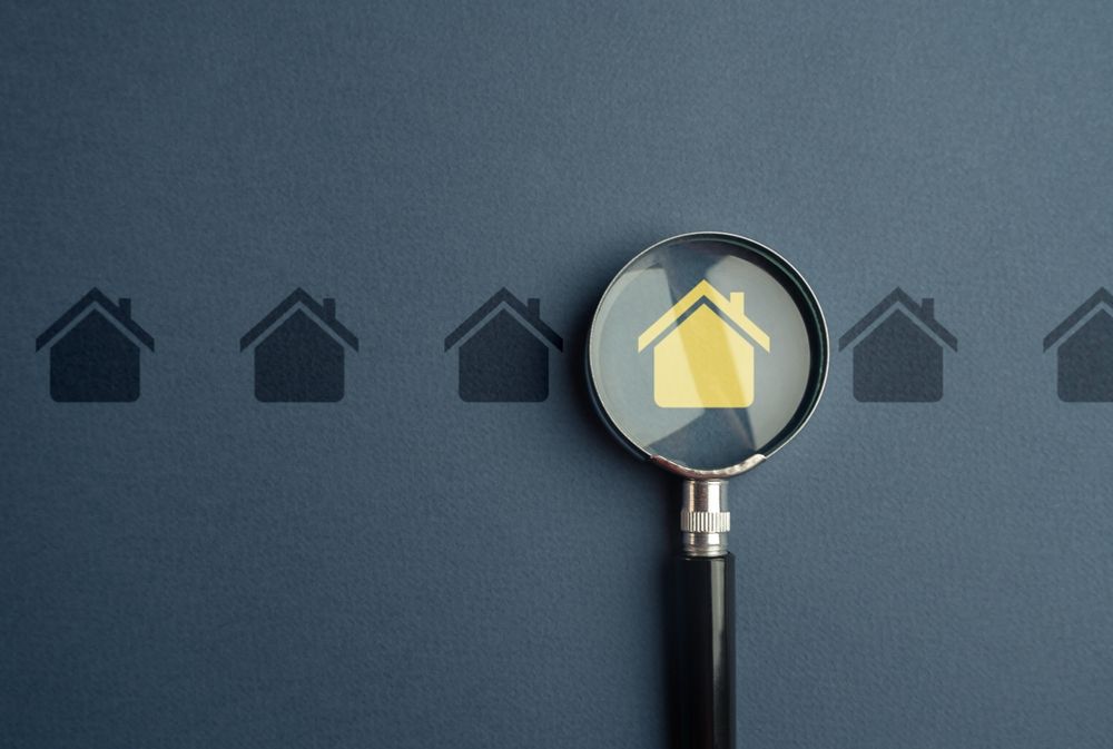 Magnifying glass over a highlighted house icon; other house icons in a row.