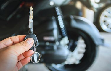 technician-holding-motorcycle-key-Infront-of-motorcycle