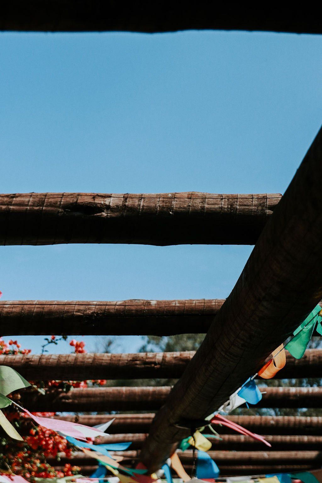 Um monte de bandeiras coloridas estão penduradas em uma estrutura de madeira.